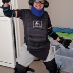 Kobieta (członkini zarządu Fundacji TUS) ubrana w symulator starości. Na oczach ma specjalne gogle a na uszach słuchawki wyciszające. Kolana i łokcie ma ubrane w siłowniki ograniczające możliwość swobodnego ruchu tymi stawami. Na tułów ma założoną kamizelkę z obciążnikami a na szyje kołnierz ortopedyczny. Na dłoniach rękawice z grubą gumą w środku. Jest szeroko uśmiechnięta i stoi w pozycji ala Krakowiaczek.