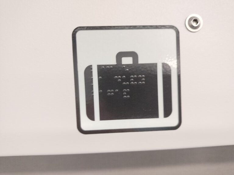 Czarny piktogram walizki opisany w alfabecie Braille'a