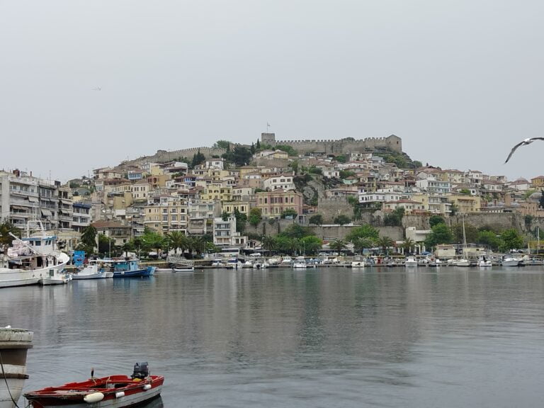 Widok z wody na kamienistą wyspę. Na wyspie typowe wyspiarskie miasteczko.